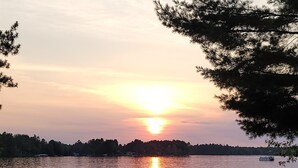 A lakeside view with a sunset, a dock with boats, and picnic tables. - Lakefront Lodging, Beach, Fire Pit, Bar & Grill, Rentals, Live Music, Trails (Tomahawk)