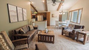 A spacious living area with a sofa, armchairs, and a coffee table. There is a kitchen area with a refrigerator and microwave, and a dining area with a table and chairs.