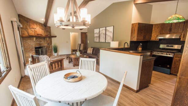 A spacious kitchen with a central island, wooden cabinets, and a stone fireplace.