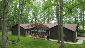 A cabin with a deck, surrounded by trees.