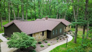 A cabin with a stone exterior and a brown roof, surrounded by a forest.