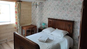Un dormitorio con una cama de madera, una mesita de noche, una lámpara y un ventanal con cortinas.