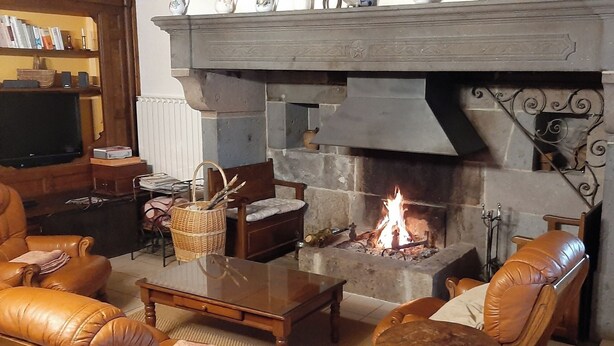 Una sala de estar acogedora con chimenea de piedra, sofás de cuero, una mesa de centro de madera y un televisor sobre un mueble.