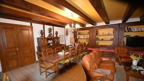 Un salón espacioso con zona de comedor, muebles de madera y una estantería.