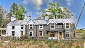 A two-story stone house with multiple windows and a chimney. - Cottage in Snowdonia With Mountain Views (Blaenau Ffestiniog)