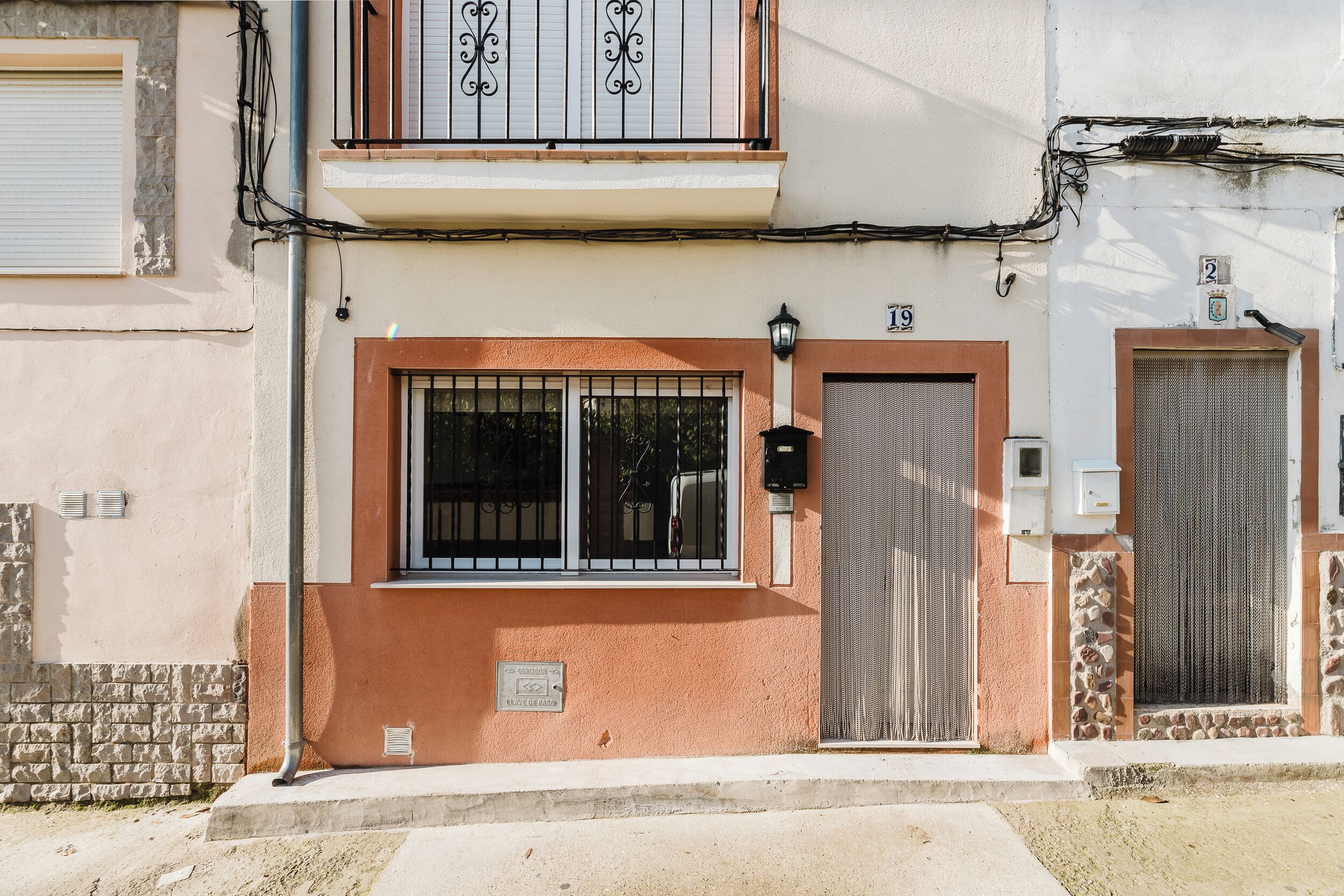 A building with a balcony, barred windows, and a door with a metal gate.