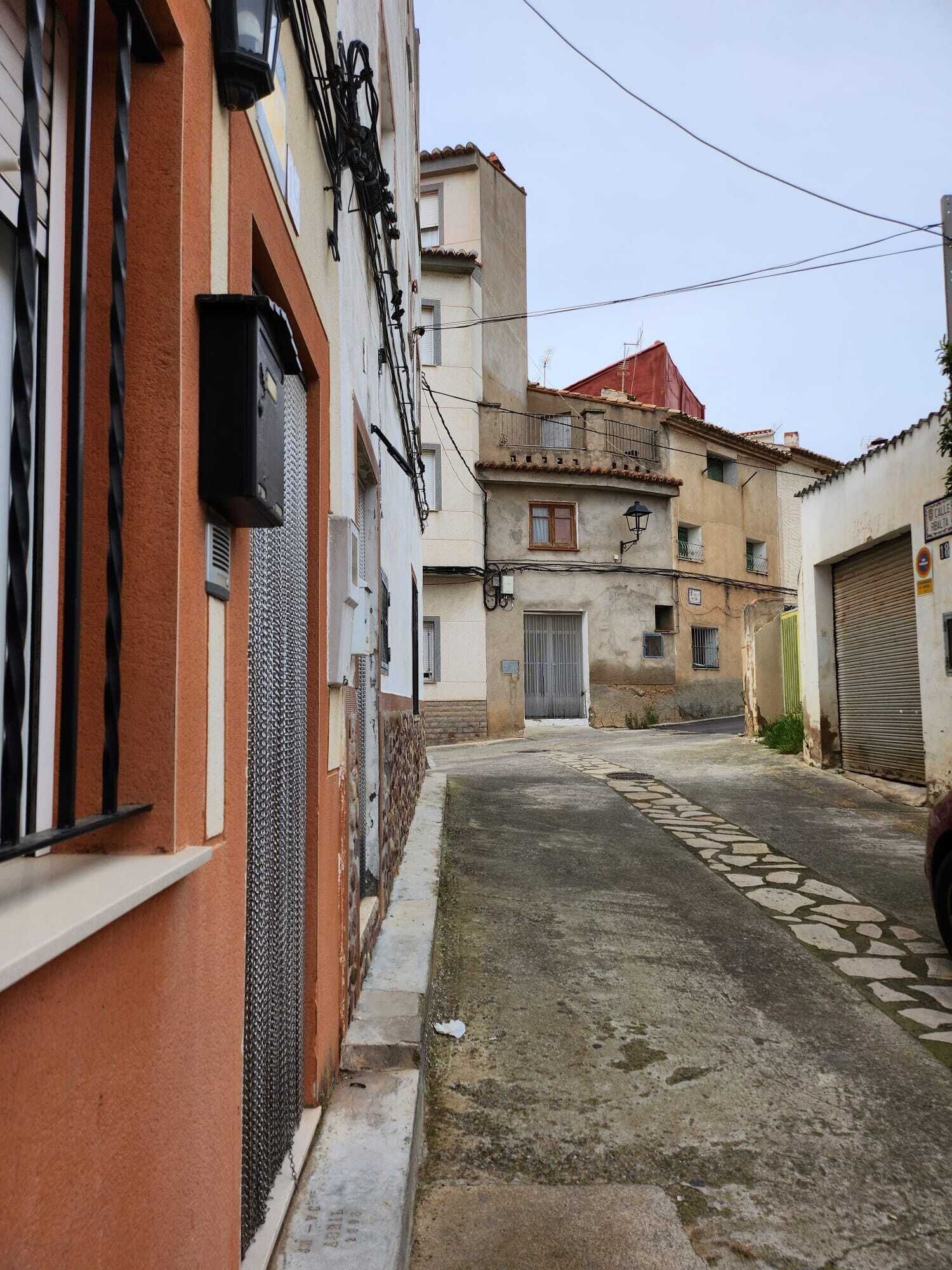 A narrow street with buildings on either side, featuring a mix of architectural styles and a cobblestone path.