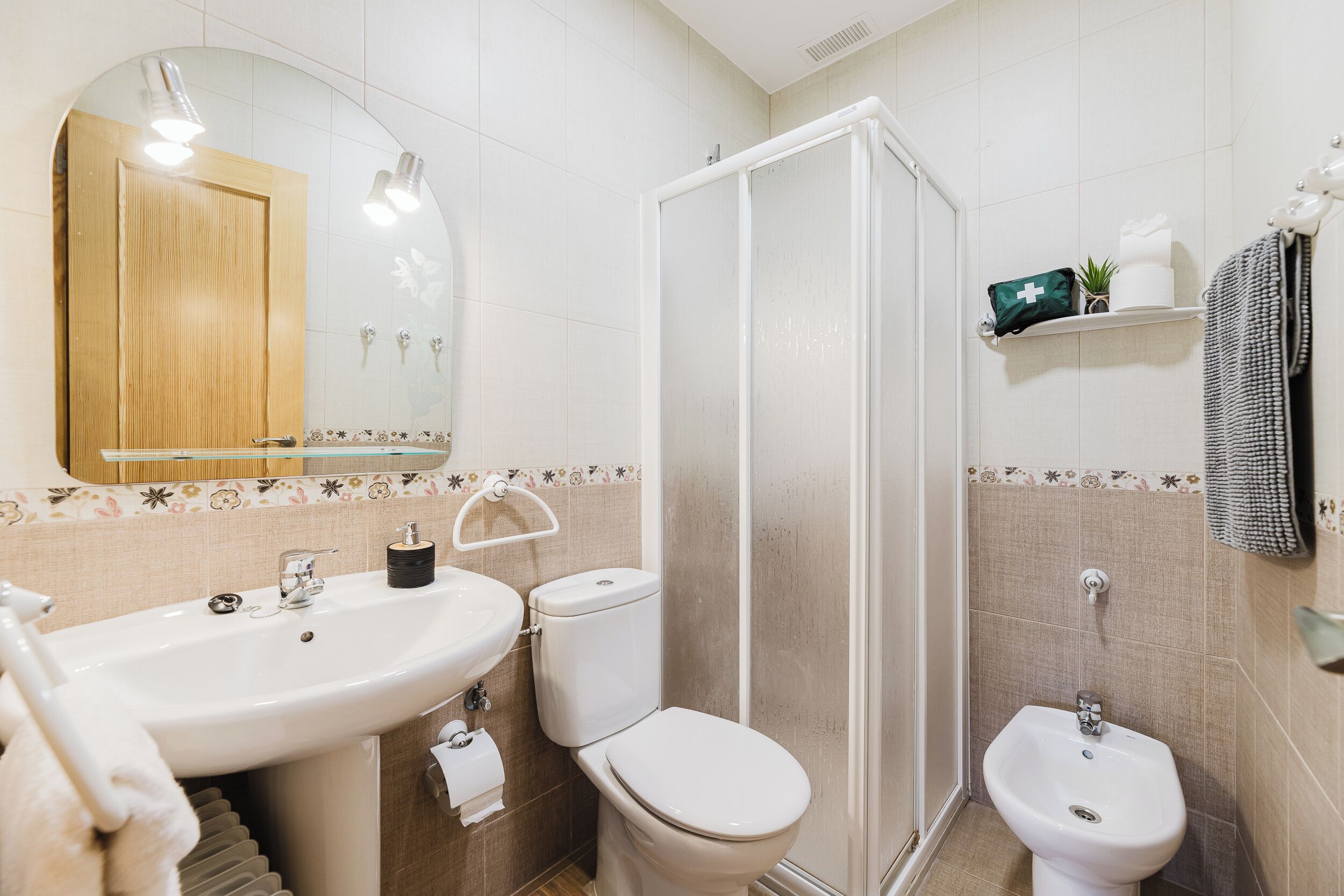 Un baño con lavamanos, inodoro, bidé y ducha.