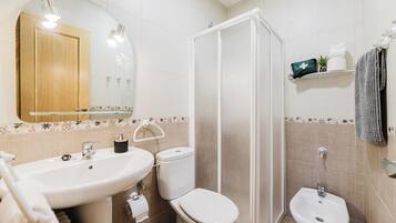 Un baño con lavamanos, inodoro, bidé y ducha.