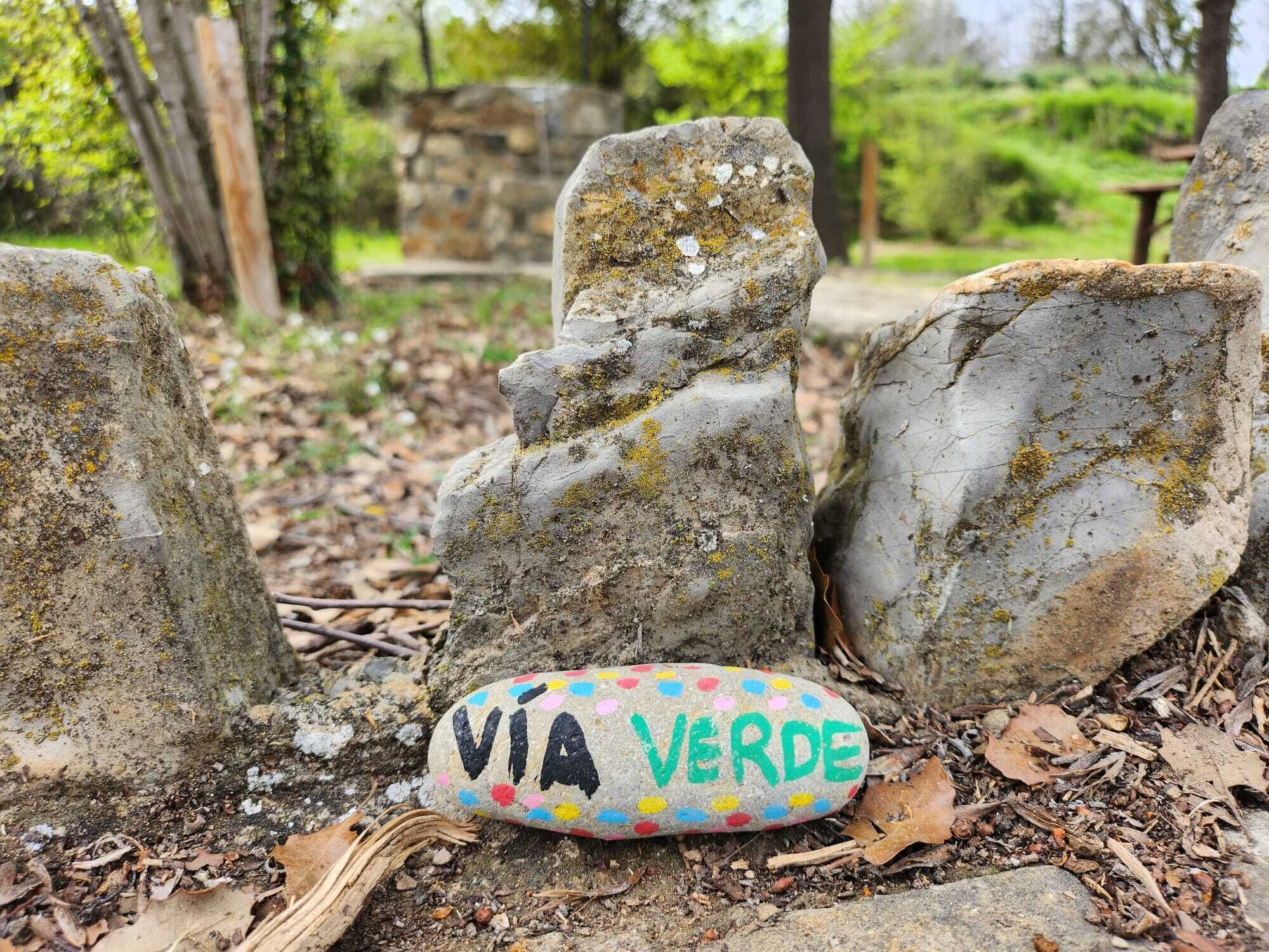Un monumento de piedra con una roca pintada que dice "VIA VERDE" en un entorno natural.