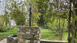 A stone structure with a stone wall and a stone bench, surrounded by trees and greenery. - Cozy house in the heart of Caudiel, 100 meters from the greenway Ojos Negros. (Caudiel)