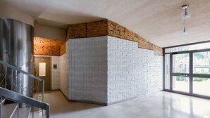 En rymlig entréhall med modern design, med en stor vägg med en unik struktur, en metalltrappa och ett stort fönster som släpper in naturligt ljus.