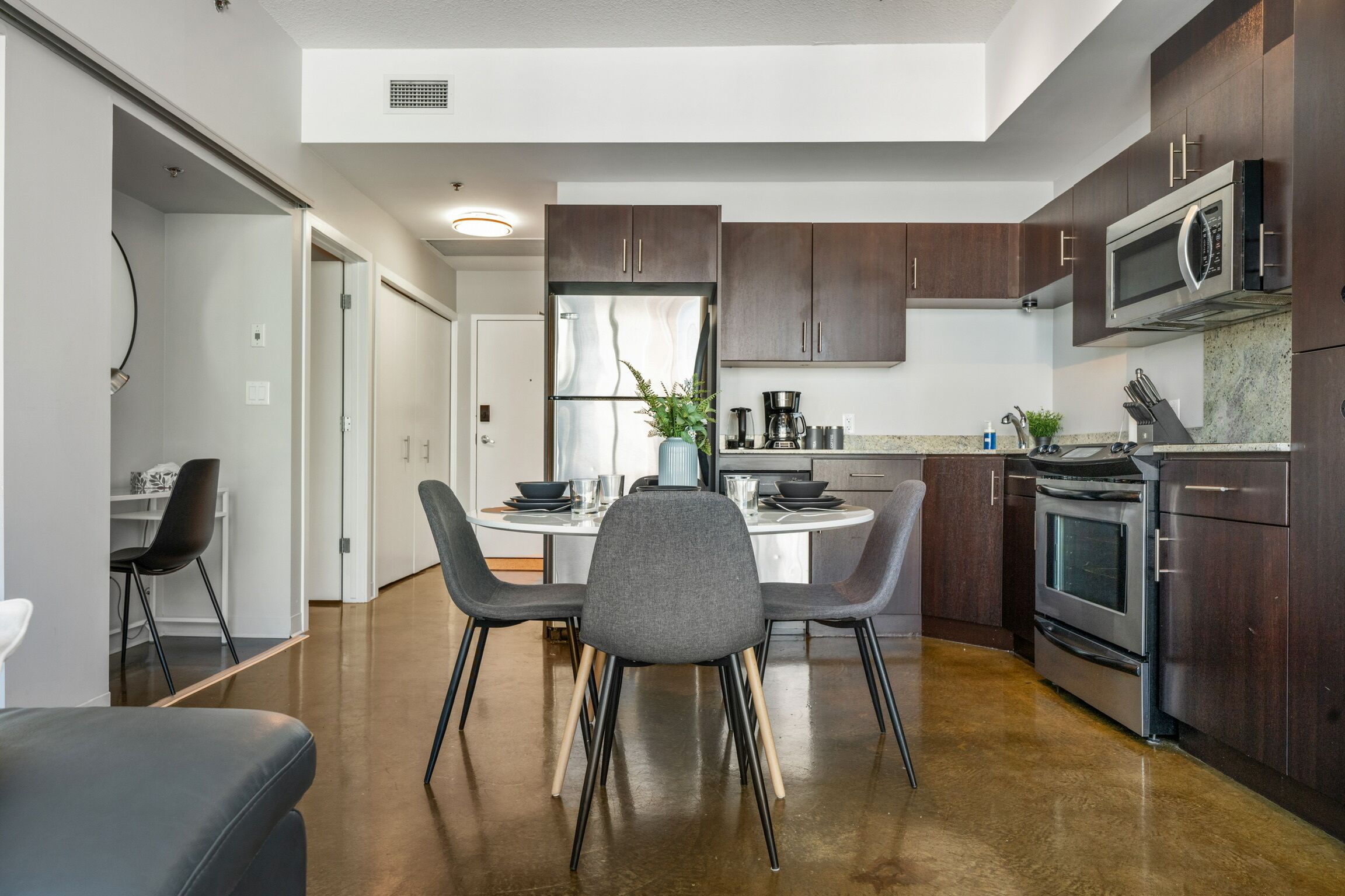 A modern kitchen with dark wood cabinets, stainless steel appliances, and a central island with seating.