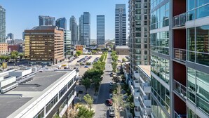 A high-rise building with a modern glass facade, a parking lot in the foreground, and other high-rise buildings in the background. - Downtown Chic Retreat | Elegant + Free Parking (Calgary)