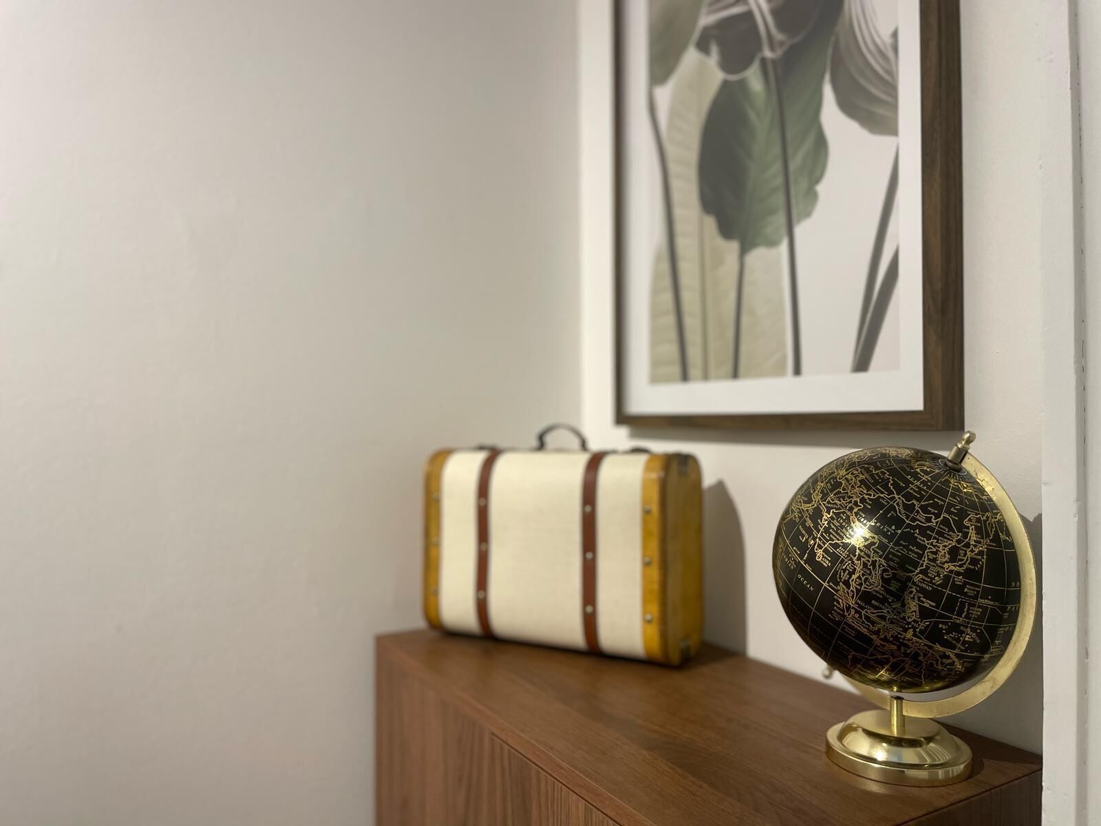 A wooden cabinet with a globe and a suitcase on top.