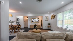 Ein modernes Wohnzimmer mit einer Couch, einem Esstisch und einem Fernseher.
