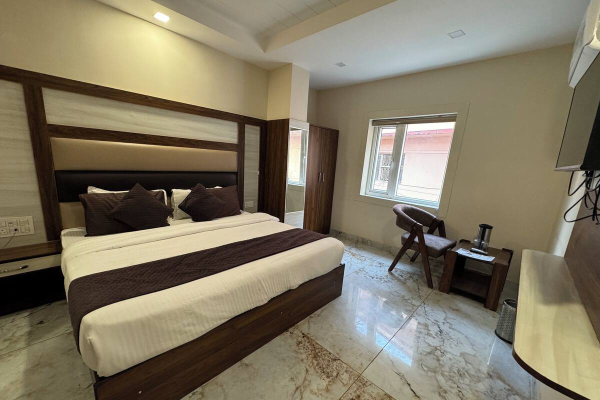 A modern bedroom with a large bed, a desk, and a TV.