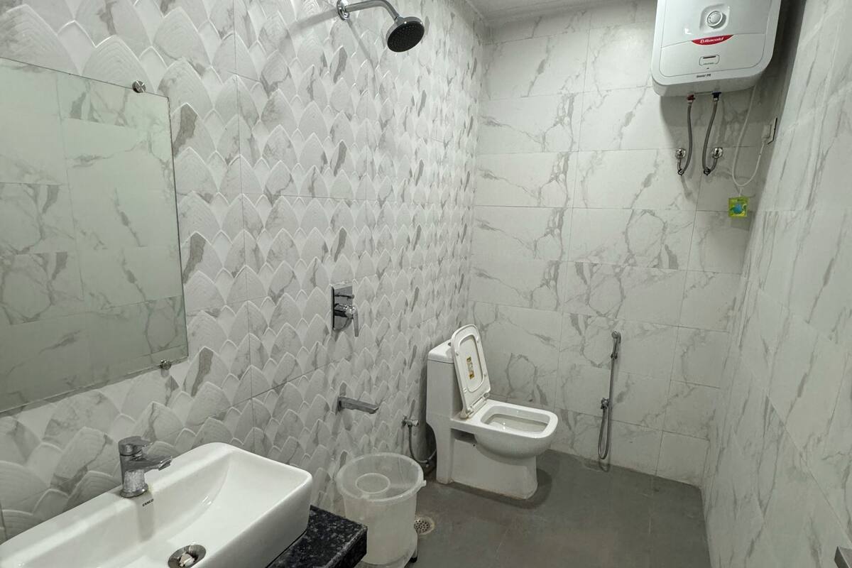 A bathroom with a sink, toilet, shower, and a wall-mounted air conditioning unit.