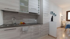 Een moderne keuken met grijze kastjes, een roestvrijstalen spoelbak en een klein fruitmandje.