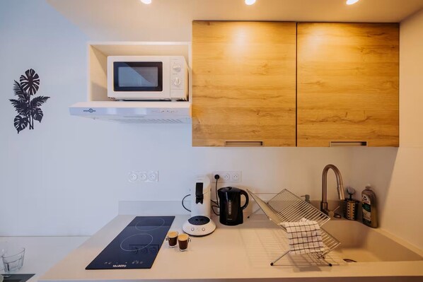 Una cocina moderna con microondas, hervidor y cafetera.