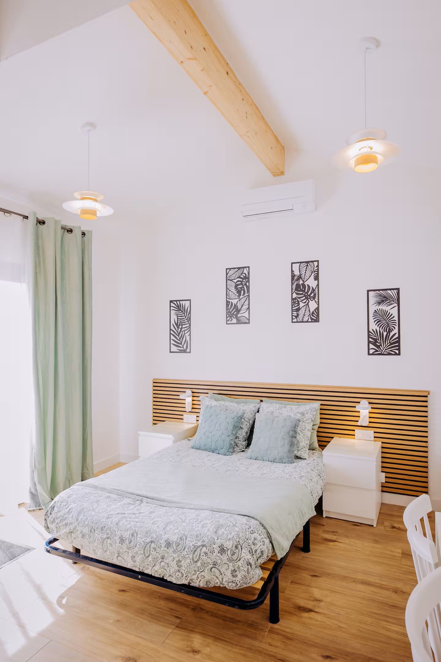 Een slaapkamer met een bed, nachtkastjes, wanddecoratie en een houten balk.