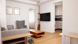 A modern living room with a grey sofa, a wooden coffee table, and a TV mounted on the wall. - Charming relax 2 bedroom apartment 200 meter to beach and 15 min bus city center (Málaga)