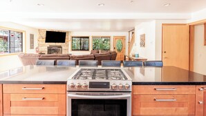 Une cuisine moderne dotée d’un grand îlot central, d’un four encastré et d’un téléviseur à écran plat.
