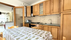 Une cuisine avec des meubles de rangement en bois, un four à micro-ondes, un évier et une table à manger avec des chaises.