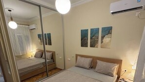 A bedroom with a large bed, a mirror, a ceiling light, and an air conditioning unit. - the New lovely Athens Central apartment (Athina)