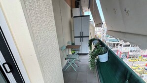 A balcony with a table and chairs, a potted plant, and a view of the street below. - the New lovely Athens Central apartment (Athina)