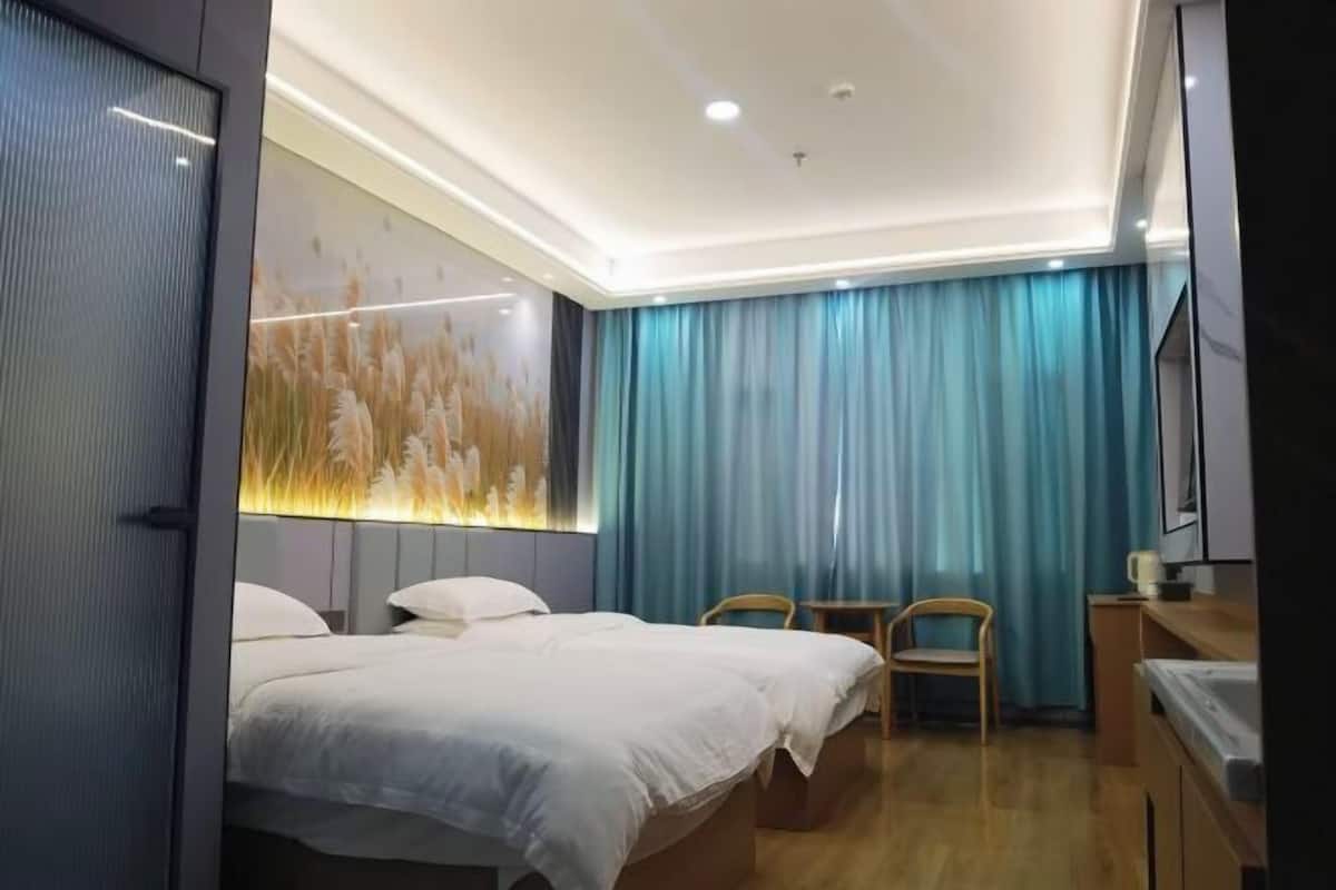 A hotel room with a bed, two chairs, a desk, and a TV.