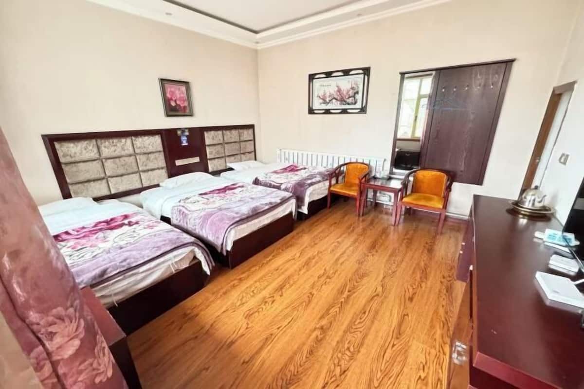 A hotel room with two beds, a wooden floor, a desk, and a chair.