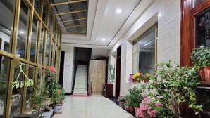 A hallway with potted plants, a staircase, and a wooden door at the end.
