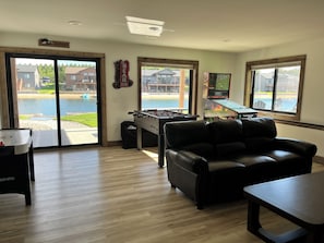 A room with a foosball table, a sofa, a foosball table, and a pool view.
