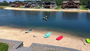 Una propiedad frente al lago con varias casas, una playa de arena y tablas de remo.