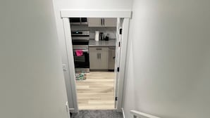 Eine Treppe führt zu einer Küche mit weißen Schränken und Holzboden.