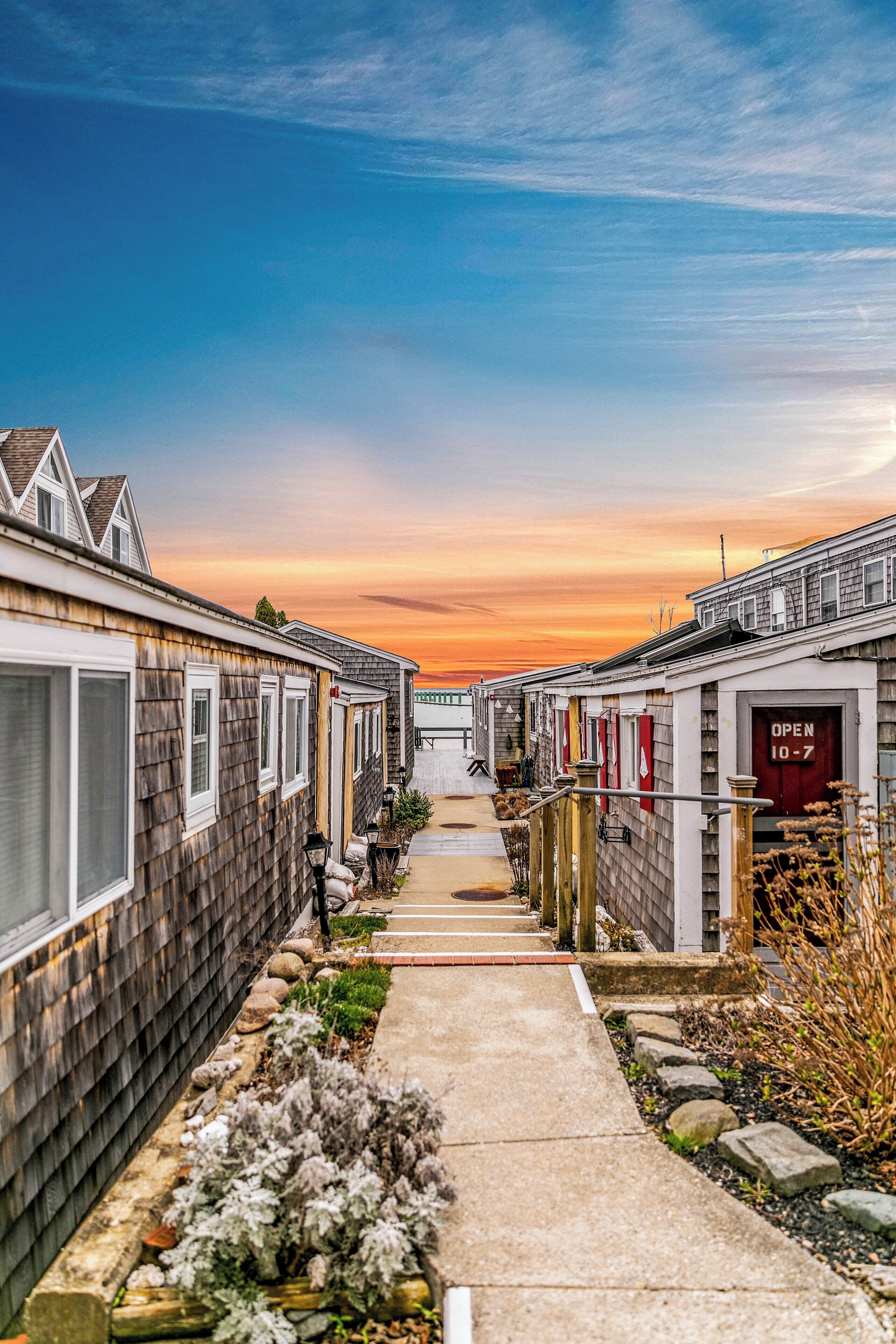 A row of wooden houses with a pathway leading to a gate.