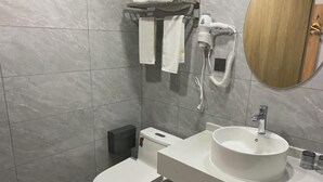 A modern bathroom with a toilet, sink, and towel rack. - Shuhao Hotel (Shanghai)