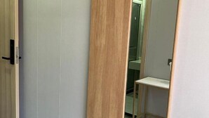 A hallway with a wooden door, a white wall, and a small wooden shelf. - Shuhao Hotel (Shanghai)
