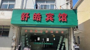 A hotel entrance with a green awning and red signage. - Shuhao Hotel (Shanghai)