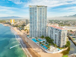 Hotel alto com várias varandas, localização à beira-mar e área de piscina.