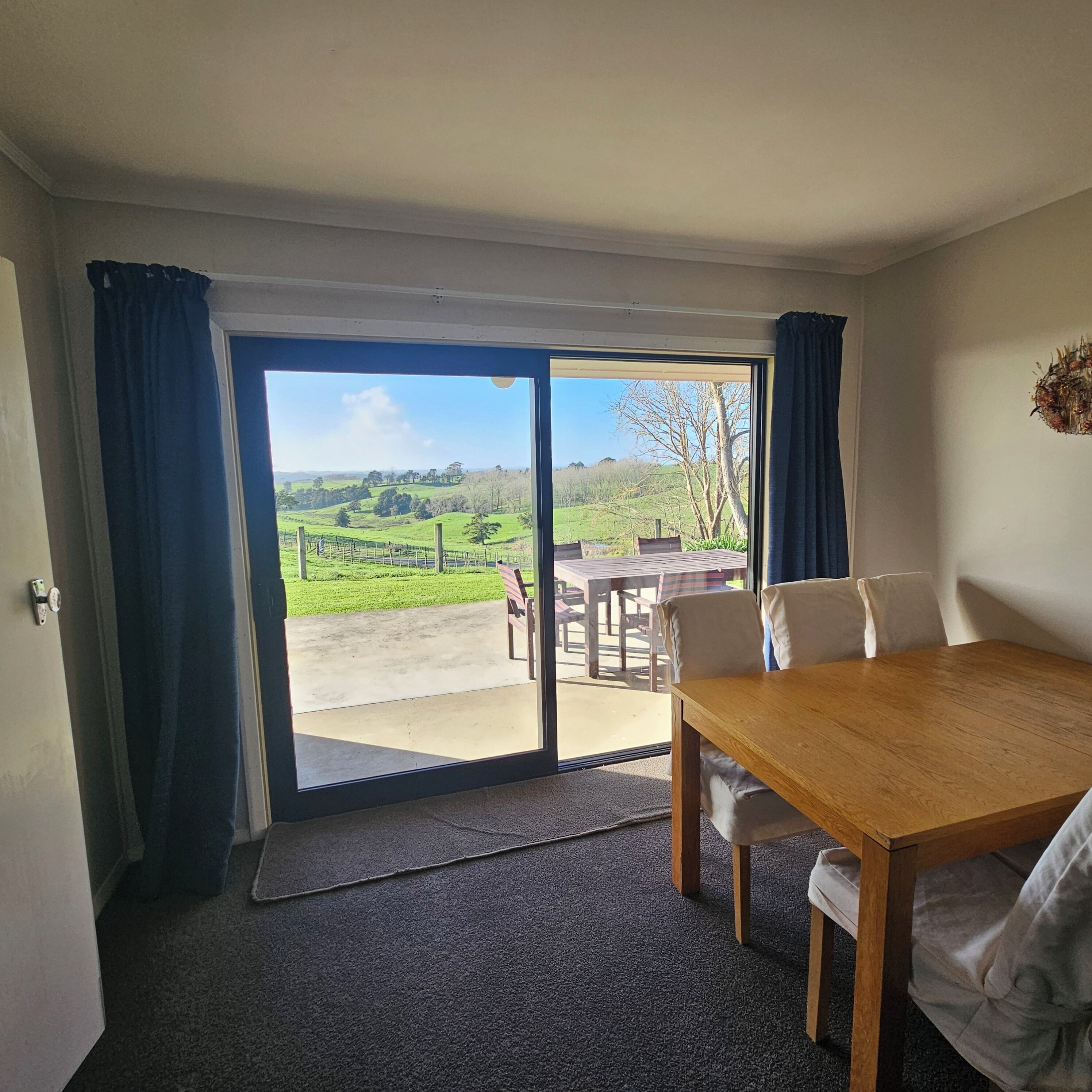 A room with a large sliding glass door leading to an outdoor area with a table and chairs.