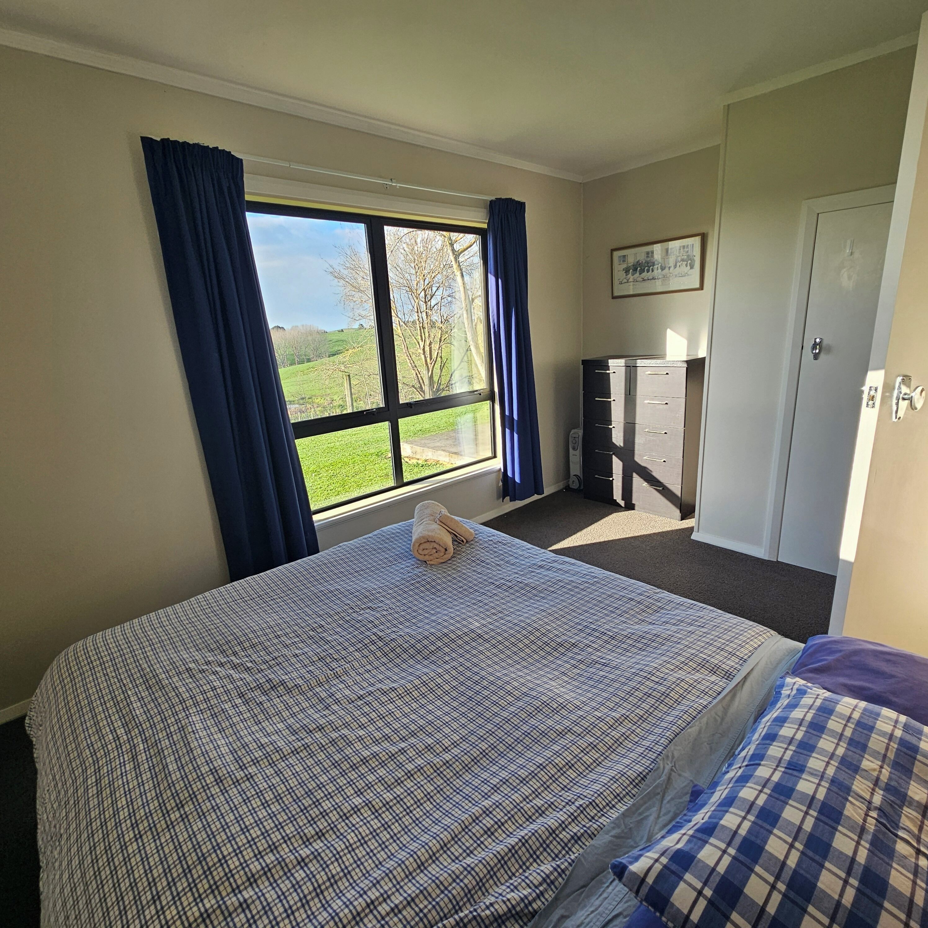 Un dormitorio con cama, ventana con cortinas, armario y puerta.