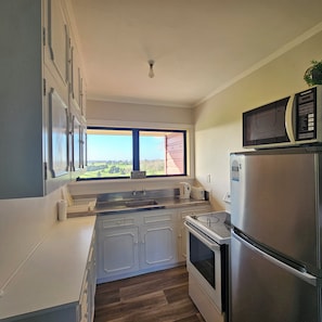 Eine Küche mit Fenster, Edelstahlgeräten und Blick auf ein rotes Gebäude.