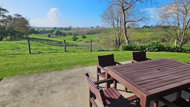 A patio with a table and chairs, a view of a green field, and a clear sky. - Forget your worries in our cosy farm cottage Spacious & relaxing with farm views (Ruawaro)
