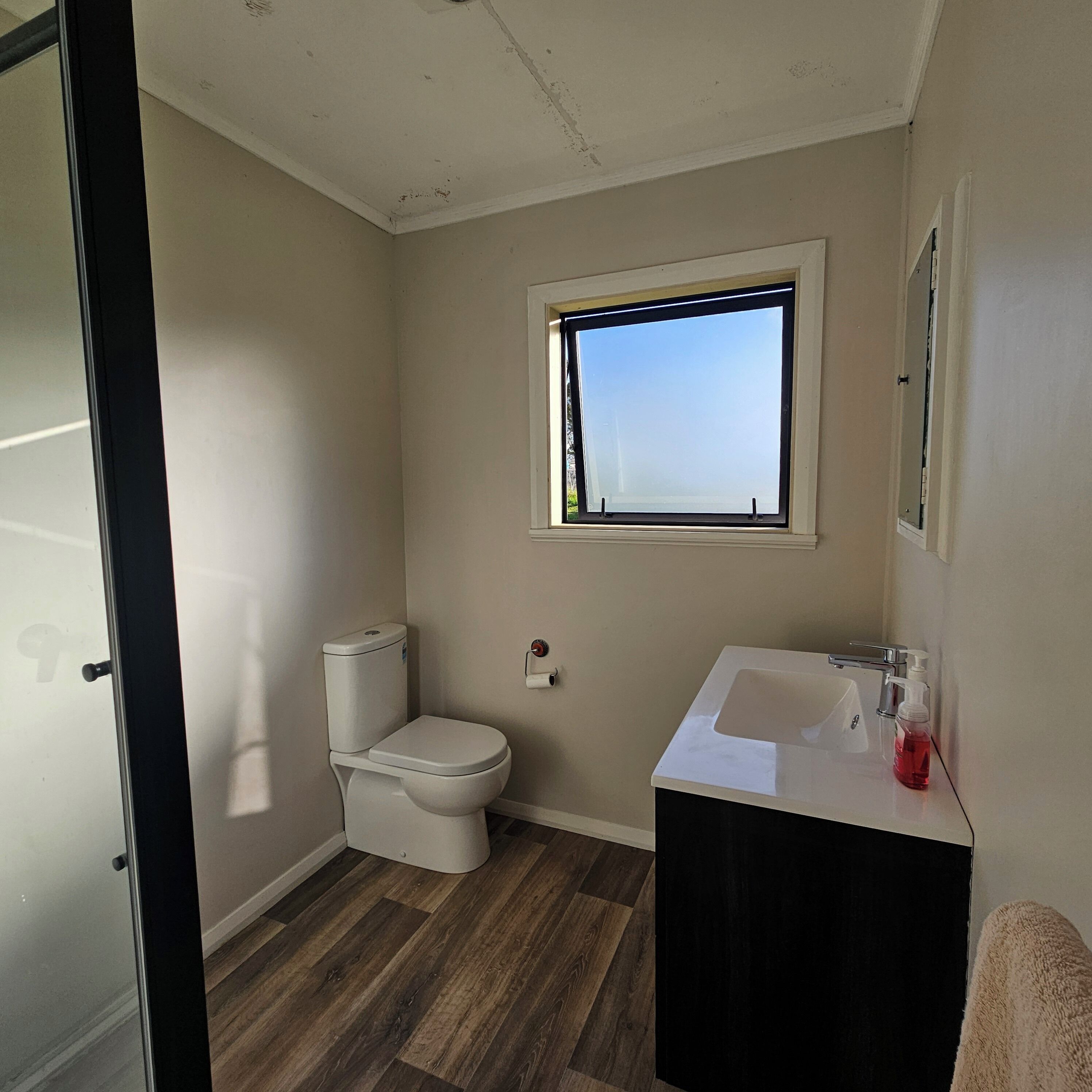 Un baño pequeño con inodoro, lavamanos y ventana.