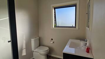 Un baño pequeño con inodoro, lavamanos y ventana.
