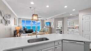 Una cocina moderna con una isla grande, armarios blancos y vista al océano.