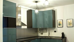 Une cuisine moderne avec des armoires de couleur turquoise, des appareils en acier inoxydable et des luminaires suspendus.