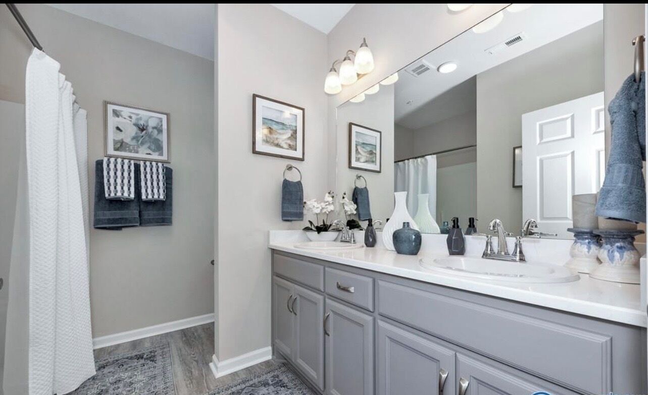 Un baño moderno con lavamanos doble, un espejo grande y toallas decorativas.